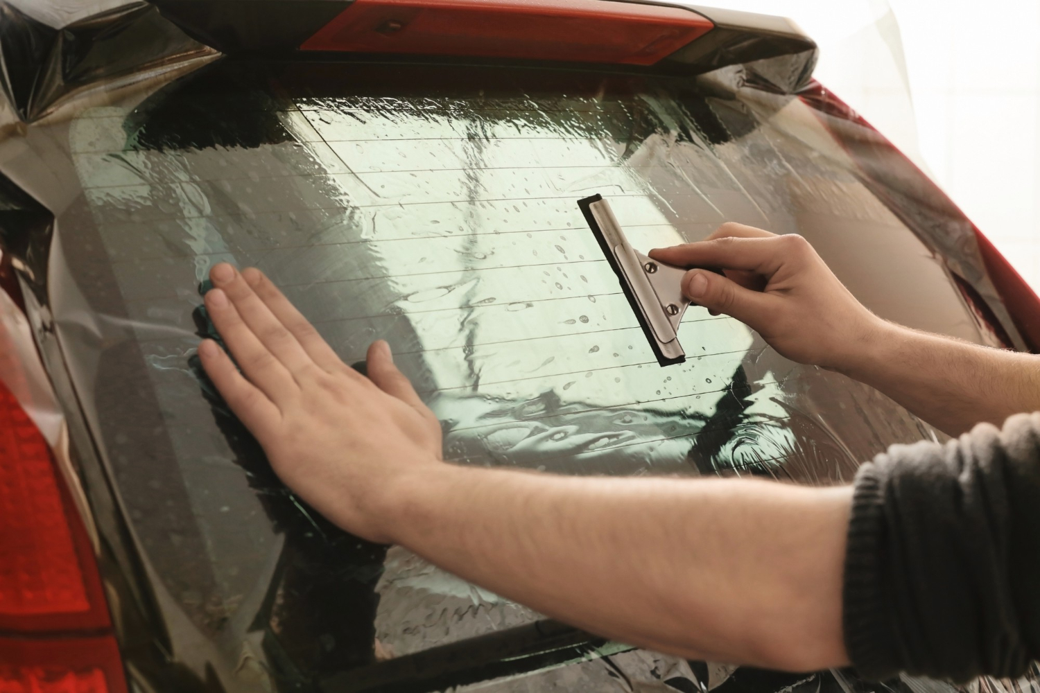 worker applying tinting foil onto car window